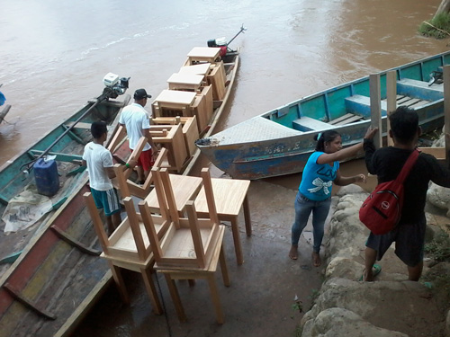 A group of people loading chairs onto a boat.