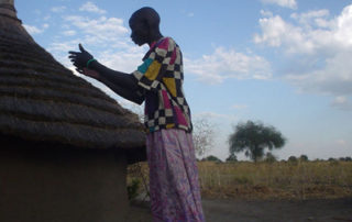A person standing in front of a hut