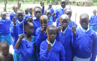 A group of children in blue shirts holding pencils.