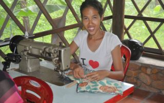 A woman sitting at a sewing machine with a bag.