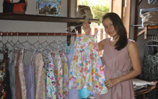 A woman standing next to a rack of dresses.