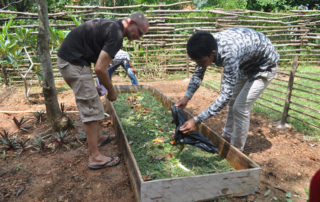 Two men working in a garden with plants.