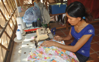 A woman sewing fabric on a table.