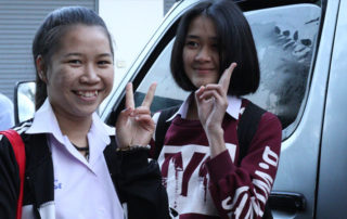 Two young women standing next to a car.