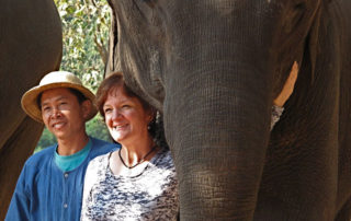 A man and woman standing next to an elephant.