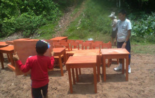 A boy and his father playing with wooden chairs.