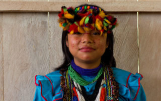 A young girl wearing colorful clothing and a hat.