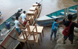 A group of people loading chairs onto boats.