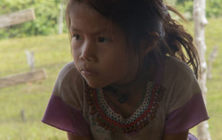A young girl sitting on the ground looking at something.