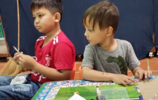 Two young boys sitting at a table playing a game.