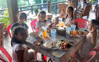 A group of children sitting at a table with food.